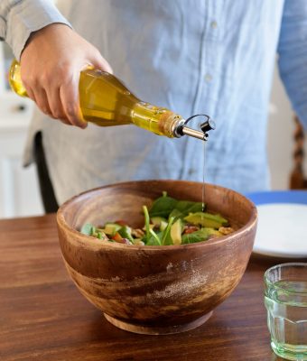 Olijfolie schenken in een kom met salade