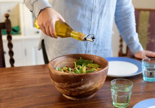 Olijfolie schenken in een kom met salade