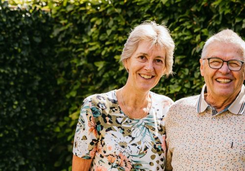 Het echtpaar Anja en Theo staan lachend in hun tuin op de foto