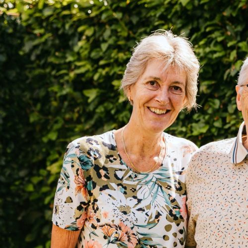 Het echtpaar Anja en Theo staan lachend in hun tuin op de foto