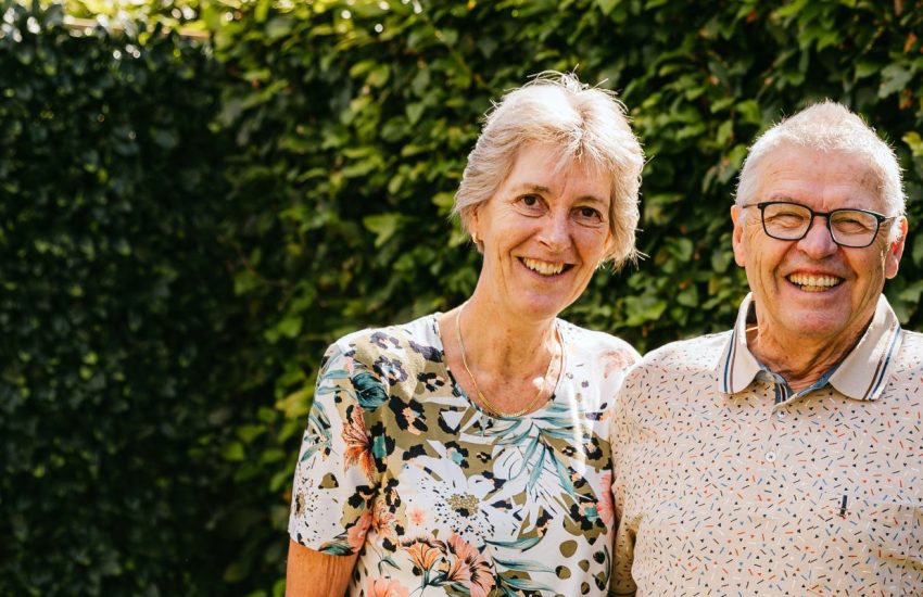 Het echtpaar Anja en Theo staan lachend in hun tuin op de foto