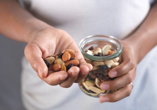Bovenaanzicht van een handje noten uit een glazen pot