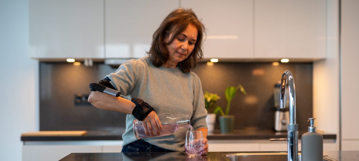 Vrouw met STIL-orthese schenkt glas in